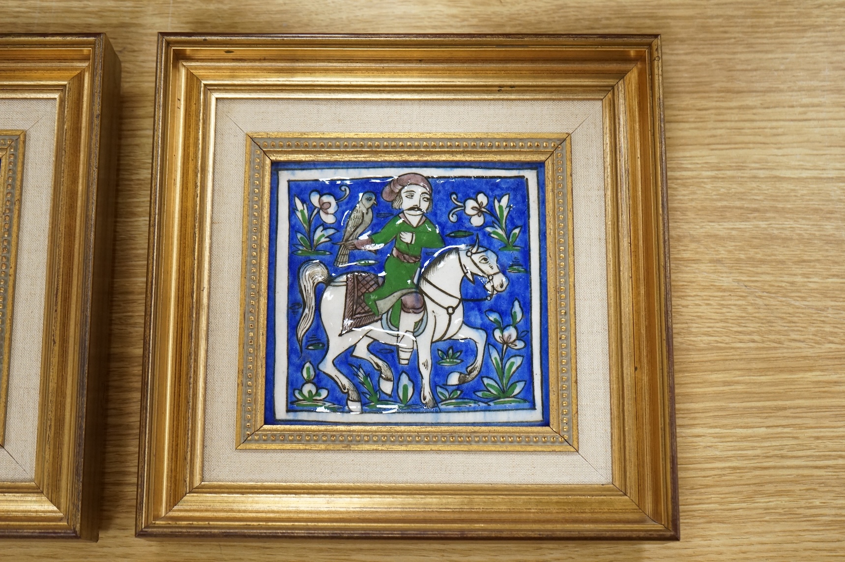 A pair of 19th century Persian fritware tiles depicting falconers, framed, 14cm squared